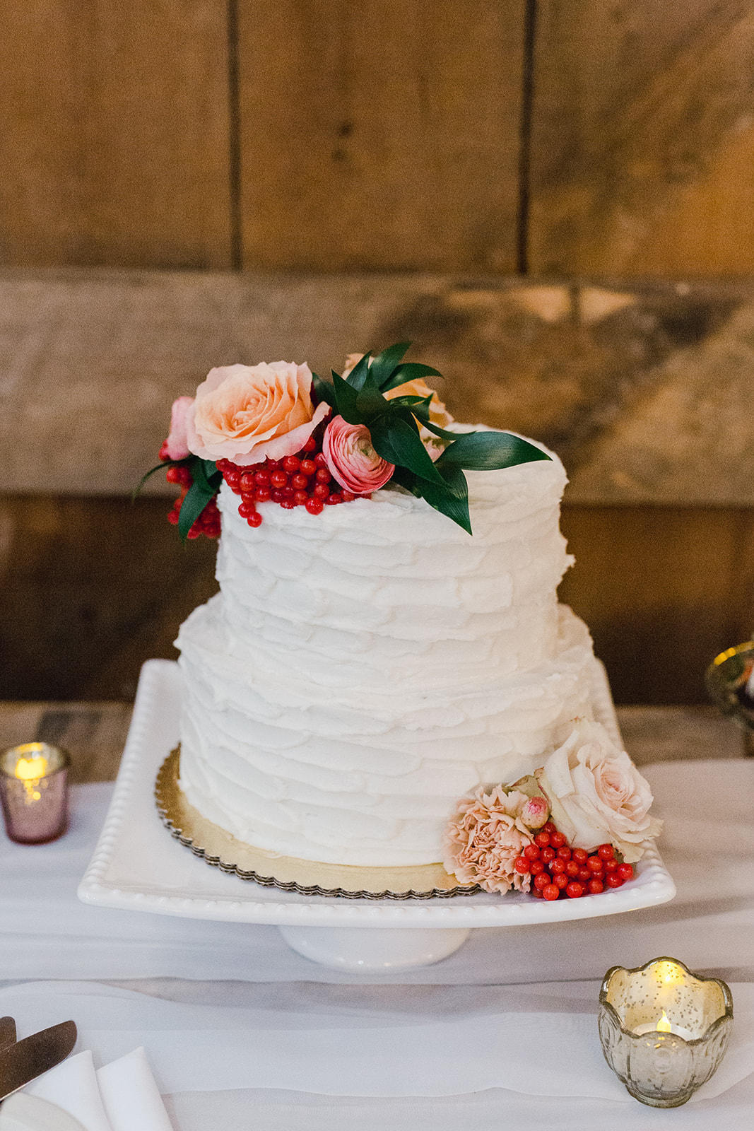 styled colorful and bright flowers on a rustic wedding cake in a barn by Studio Fleurette.