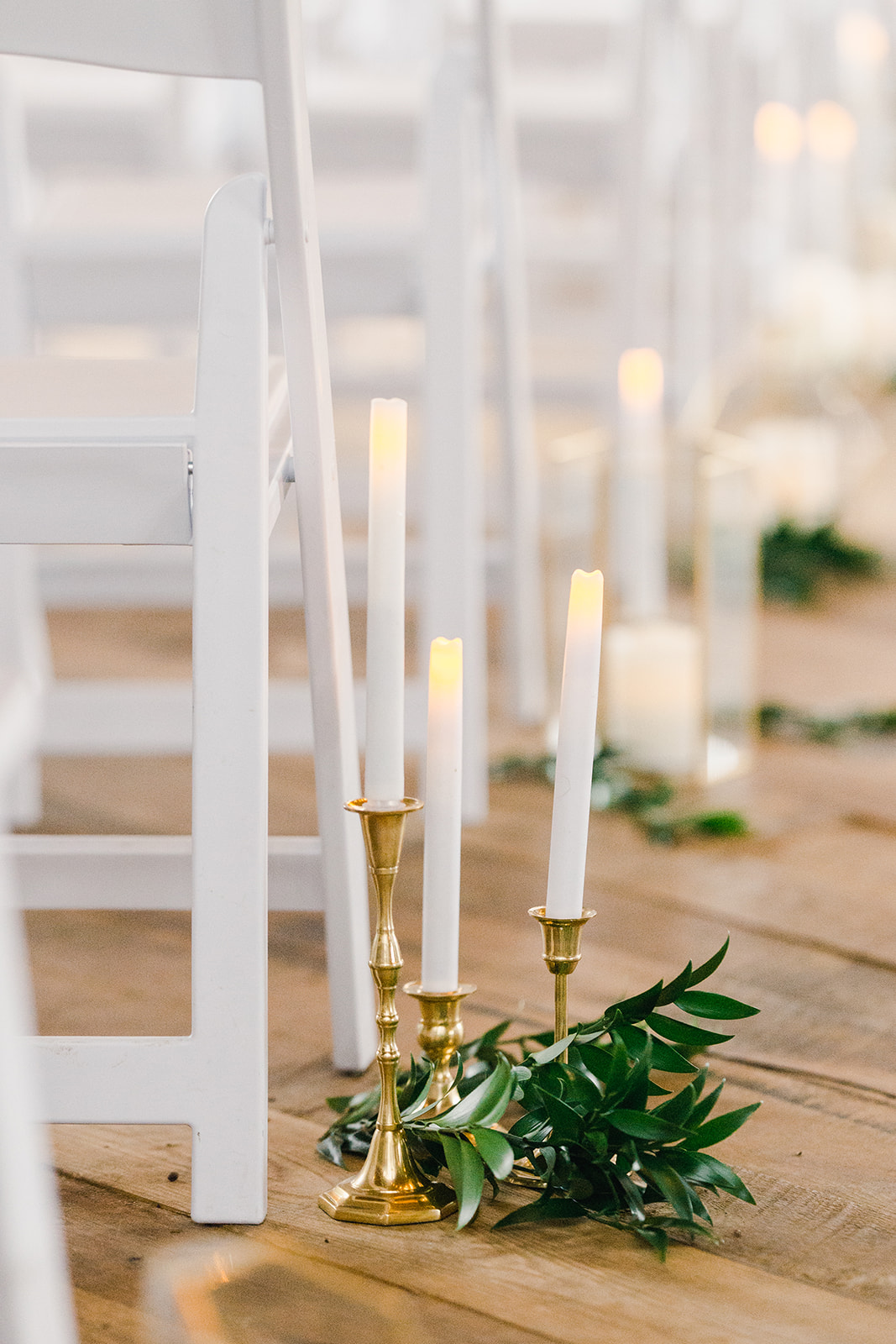 wedding ceremony aisle decor with gold candlesticks, taper candles and styled greenery by Studio Fleurette in a barn wedding in Wisconsin.