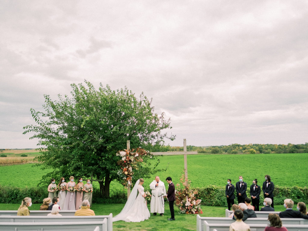 Outdoor wedding ceremony at Legacy Hill Farm with arch flowers by Studio Fleurette.